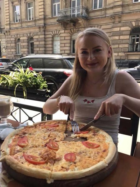 A young woman eating a pizza on a patio