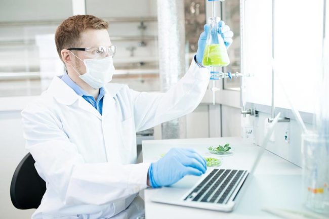 A male research is holding a flask in the lab